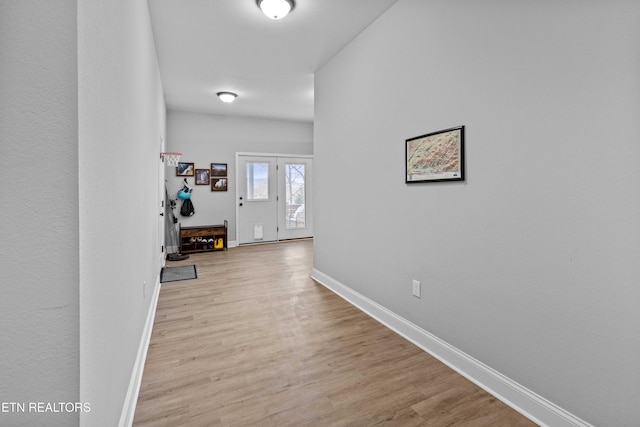 hallway featuring light wood-style floors and baseboards