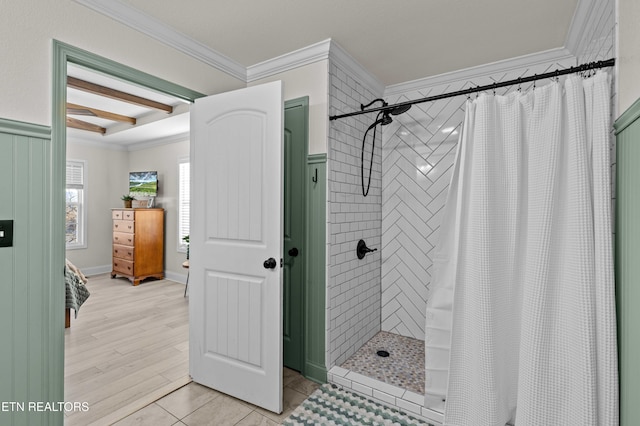 bathroom with tiled shower, crown molding, beamed ceiling, and wood finished floors