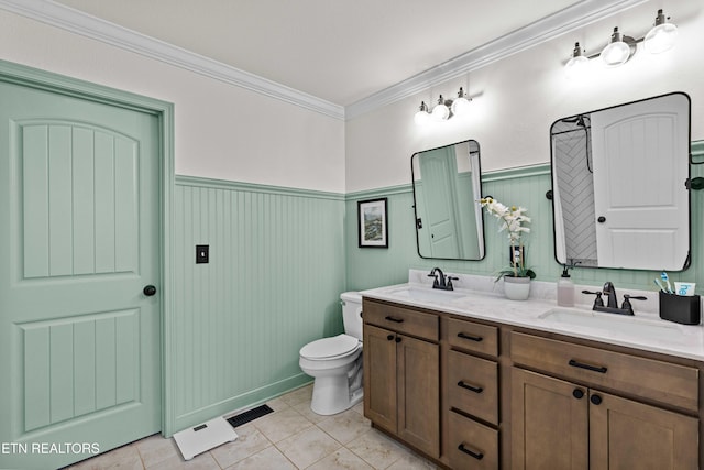 bathroom featuring toilet, a wainscoted wall, visible vents, and a sink