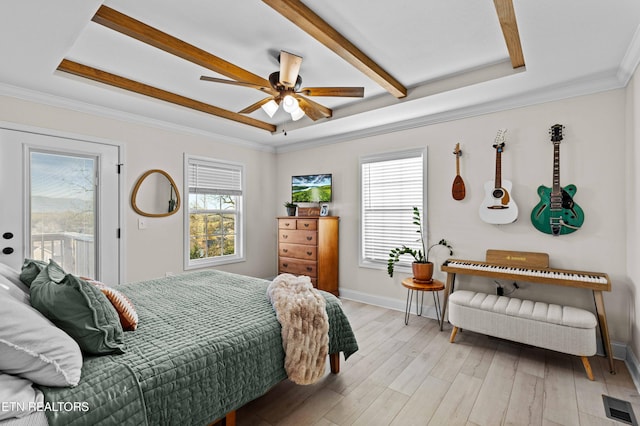 bedroom with light wood finished floors, a tray ceiling, multiple windows, and visible vents