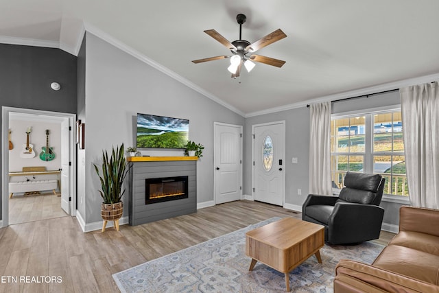 living area featuring a glass covered fireplace, crown molding, and wood finished floors