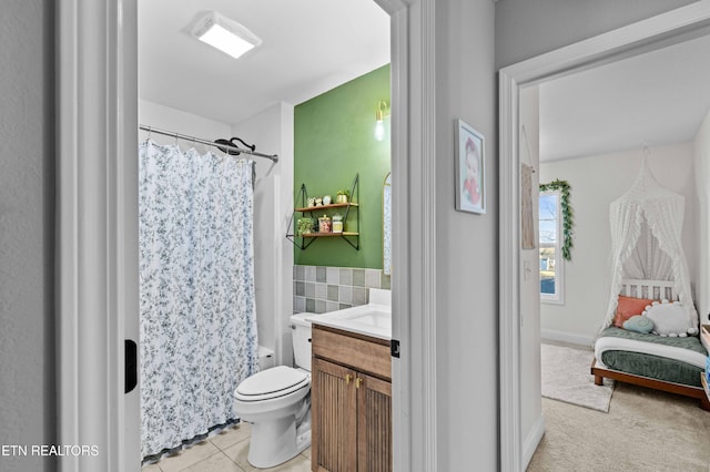 bathroom with toilet, a shower with curtain, tile patterned floors, vanity, and tile walls