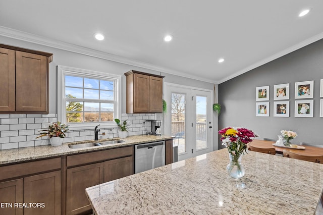 kitchen with a sink, vaulted ceiling, stainless steel dishwasher, backsplash, and crown molding