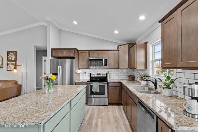 kitchen featuring crown molding, stainless steel appliances, lofted ceiling, light wood-style flooring, and a sink