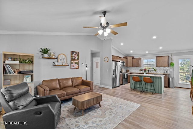 living area with lofted ceiling, light wood-style floors, ceiling fan, and ornamental molding