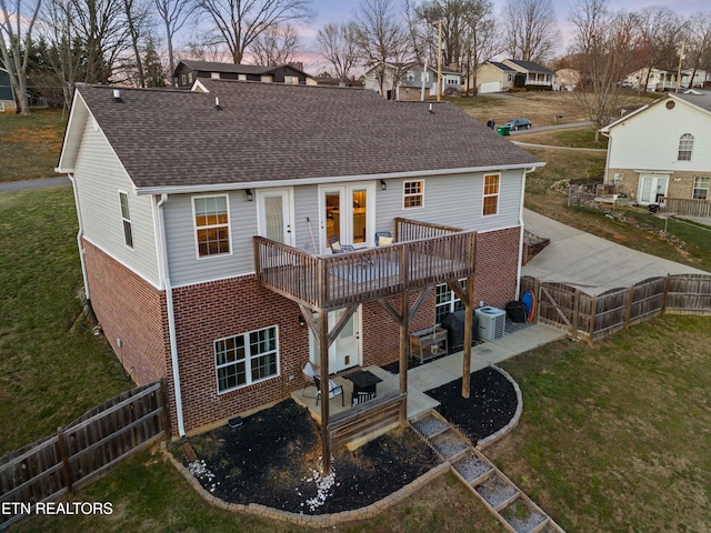 back of house featuring a patio area, brick siding, a yard, and roof with shingles