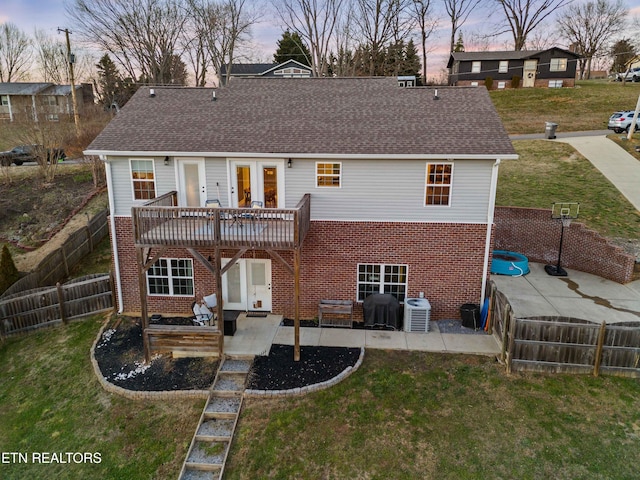 back of property at dusk with french doors, brick siding, and a yard