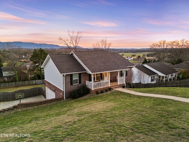 ranch-style home featuring a porch, brick siding, fence, and a lawn