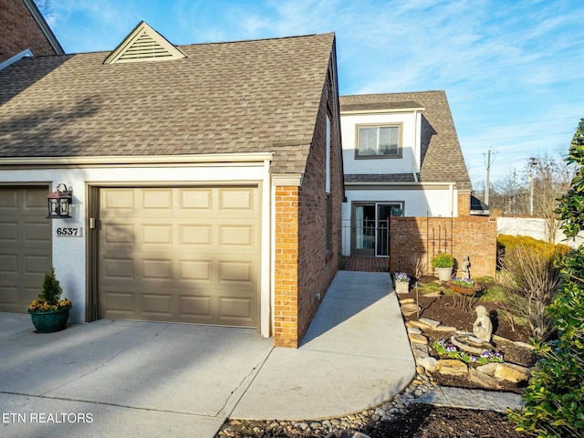 view of front facade featuring concrete driveway, an attached garage, brick siding, and a shingled roof