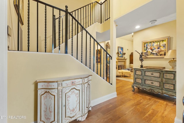 stairway featuring recessed lighting, wood finished floors, and baseboards