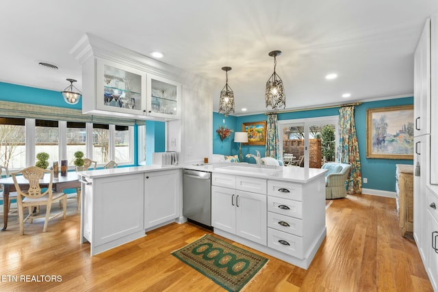 kitchen with stainless steel dishwasher, a peninsula, white cabinetry, and a sink