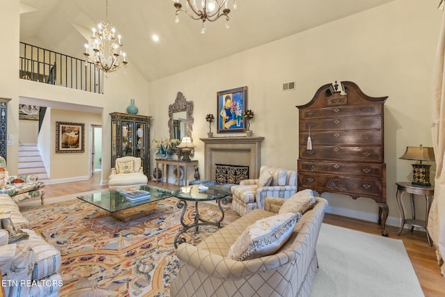 living room with visible vents, baseboards, stairs, light wood-style floors, and an inviting chandelier