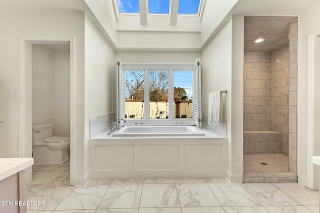 bathroom featuring toilet, marble finish floor, a stall shower, a skylight, and a bath