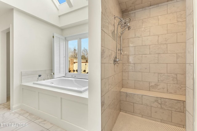 bathroom featuring a garden tub, a skylight, marble finish floor, and a tile shower