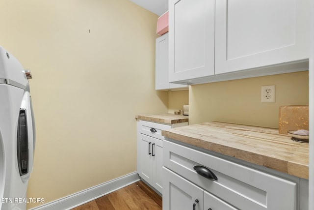 interior space featuring wood finished floors, white cabinetry, butcher block counters, baseboards, and washer / dryer