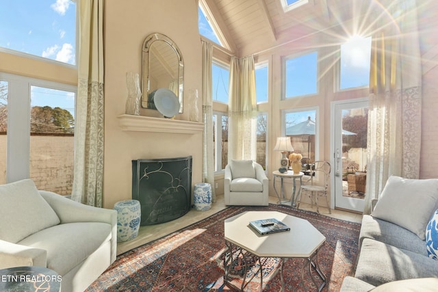 living area featuring wooden ceiling, a fireplace, and high vaulted ceiling