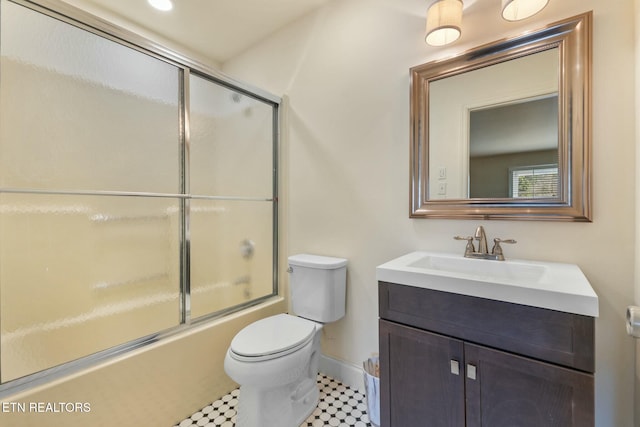 bathroom featuring baseboards, enclosed tub / shower combo, toilet, and vanity