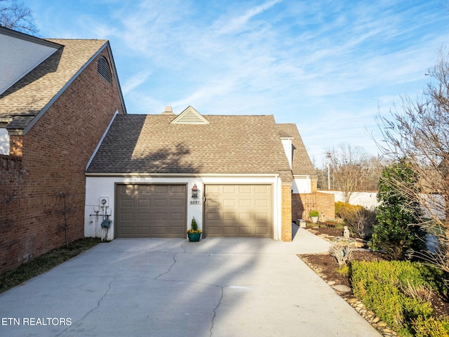 view of side of home featuring a chimney, concrete driveway, a garage, and roof with shingles