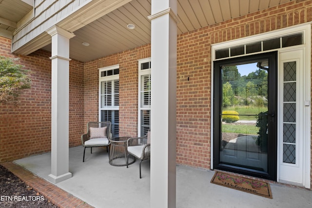 entrance to property with covered porch and brick siding