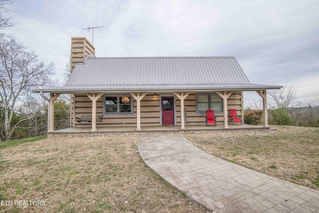 log cabin featuring metal roof, a chimney, and a porch