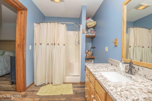 full bath with vanity, a shower with shower curtain, wood finished floors, and visible vents