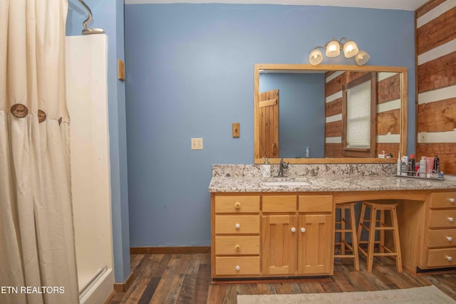 bathroom featuring curtained shower, baseboards, wood finished floors, and vanity