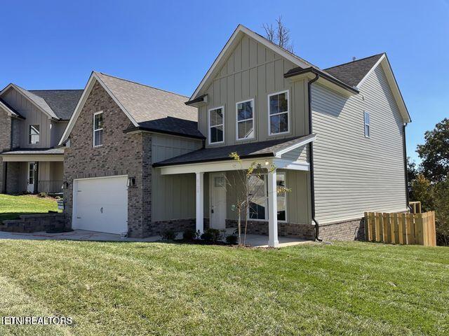 view of front of property featuring an attached garage, fence, a front yard, board and batten siding, and brick siding