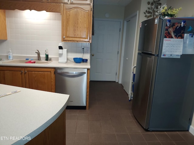 kitchen with a sink, light countertops, appliances with stainless steel finishes, tasteful backsplash, and brown cabinetry