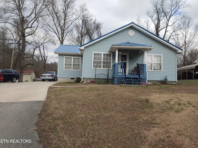 view of front of property featuring metal roof, aphalt driveway, crawl space, and a front yard