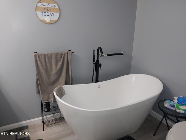 bathroom with a freestanding tub and baseboards