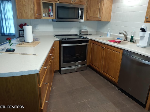 kitchen featuring appliances with stainless steel finishes, brown cabinets, a sink, and decorative backsplash