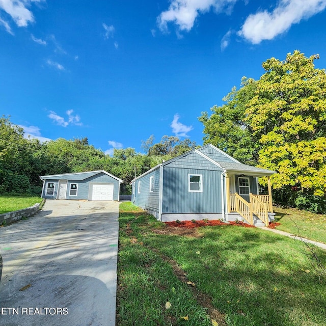 view of front of house featuring a detached garage, board and batten siding, a front yard, an outdoor structure, and driveway