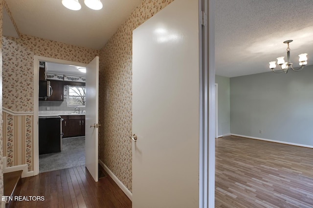 610 Hudson St, Athens, TN 37303 - hall featuring a textured ceiling, wood finished floors, baseboards, wallpapered walls, and an inviting chandelier