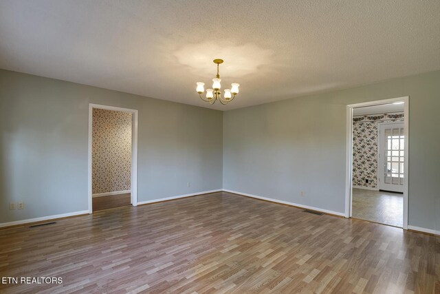 610 Hudson St, Athens, TN 37303 - empty room with visible vents, an inviting chandelier, a textured ceiling, wood finished floors, and baseboards