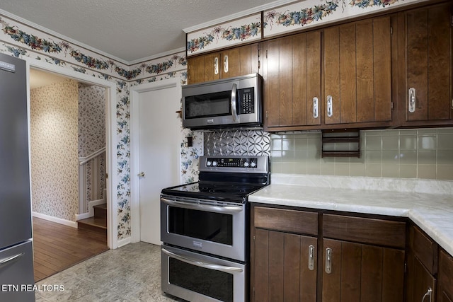610 Hudson St, Athens, TN 37303 - kitchen featuring wallpapered walls, tasteful backsplash, appliances with stainless steel finishes, light countertops, and a textured ceiling