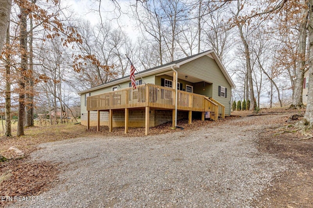 view of front facade featuring driveway, stairs, and a wooden deck