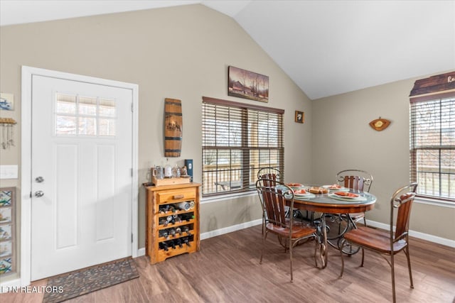 dining room with lofted ceiling, wood finished floors, and baseboards