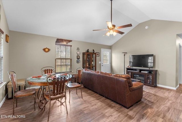 living room with vaulted ceiling, light wood finished floors, a ceiling fan, and baseboards