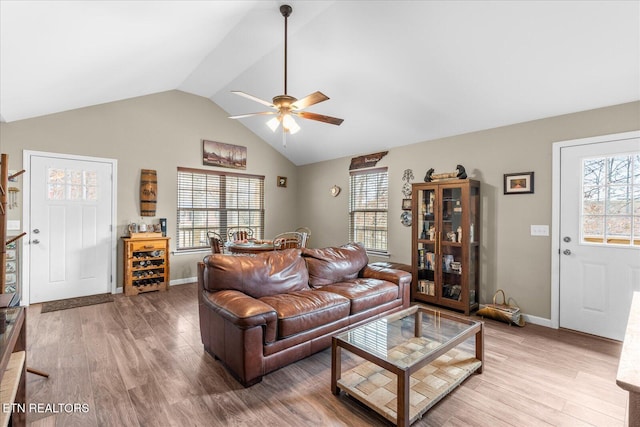 living room with lofted ceiling, ceiling fan, light wood-style flooring, and baseboards