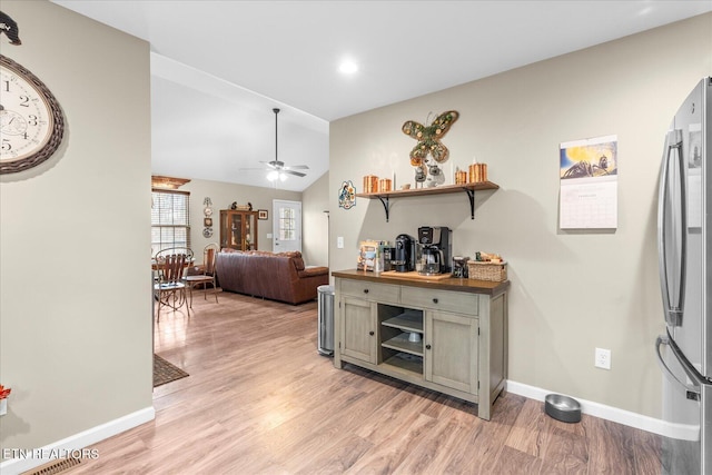 interior space with freestanding refrigerator, baseboards, lofted ceiling, and light wood finished floors