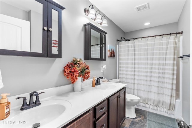 bathroom with visible vents, a sink, toilet, and double vanity