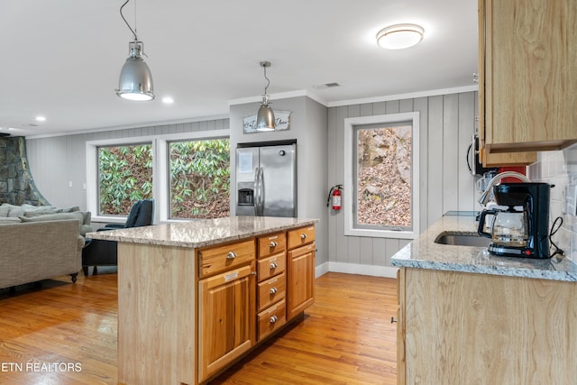 kitchen with stainless steel appliances, visible vents, ornamental molding, light stone countertops, and light wood finished floors