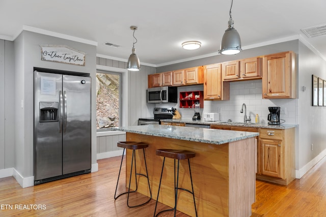 kitchen with appliances with stainless steel finishes, light wood-style floors, visible vents, and ornamental molding