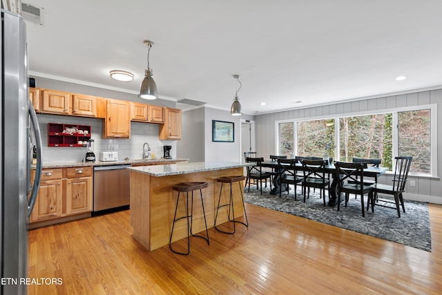 kitchen featuring light wood-style floors, tasteful backsplash, stainless steel appliances, and a sink