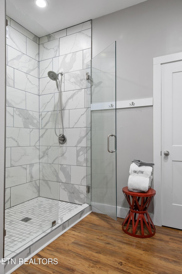 full bathroom featuring a shower stall and wood finished floors