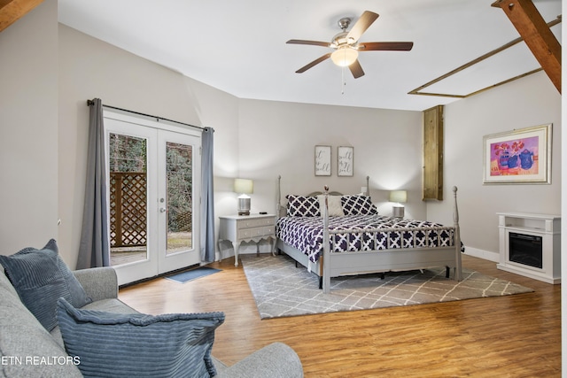 bedroom featuring baseboards, wood finished floors, access to outside, french doors, and a fireplace