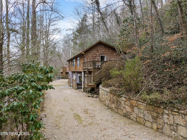 view of side of home with stairs, driveway, and a deck