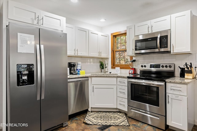 kitchen with stainless steel appliances, backsplash, a sink, and white cabinets