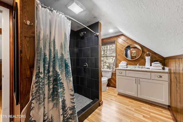 full bath featuring a stall shower, wooden walls, wood finished floors, and a textured ceiling