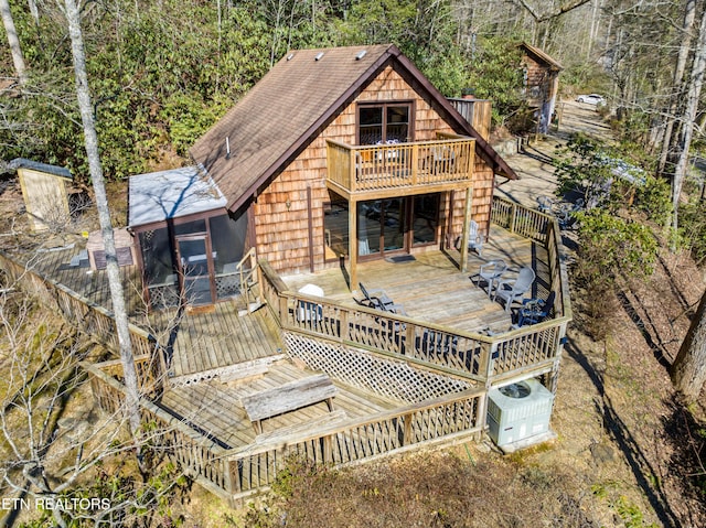 rear view of house featuring a deck, a sunroom, and a balcony